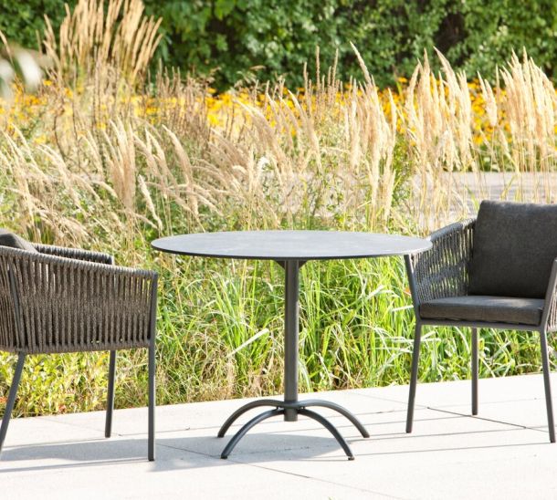 Gartentisch und Stühle auf Terrasse mit Gräsern und Blumen